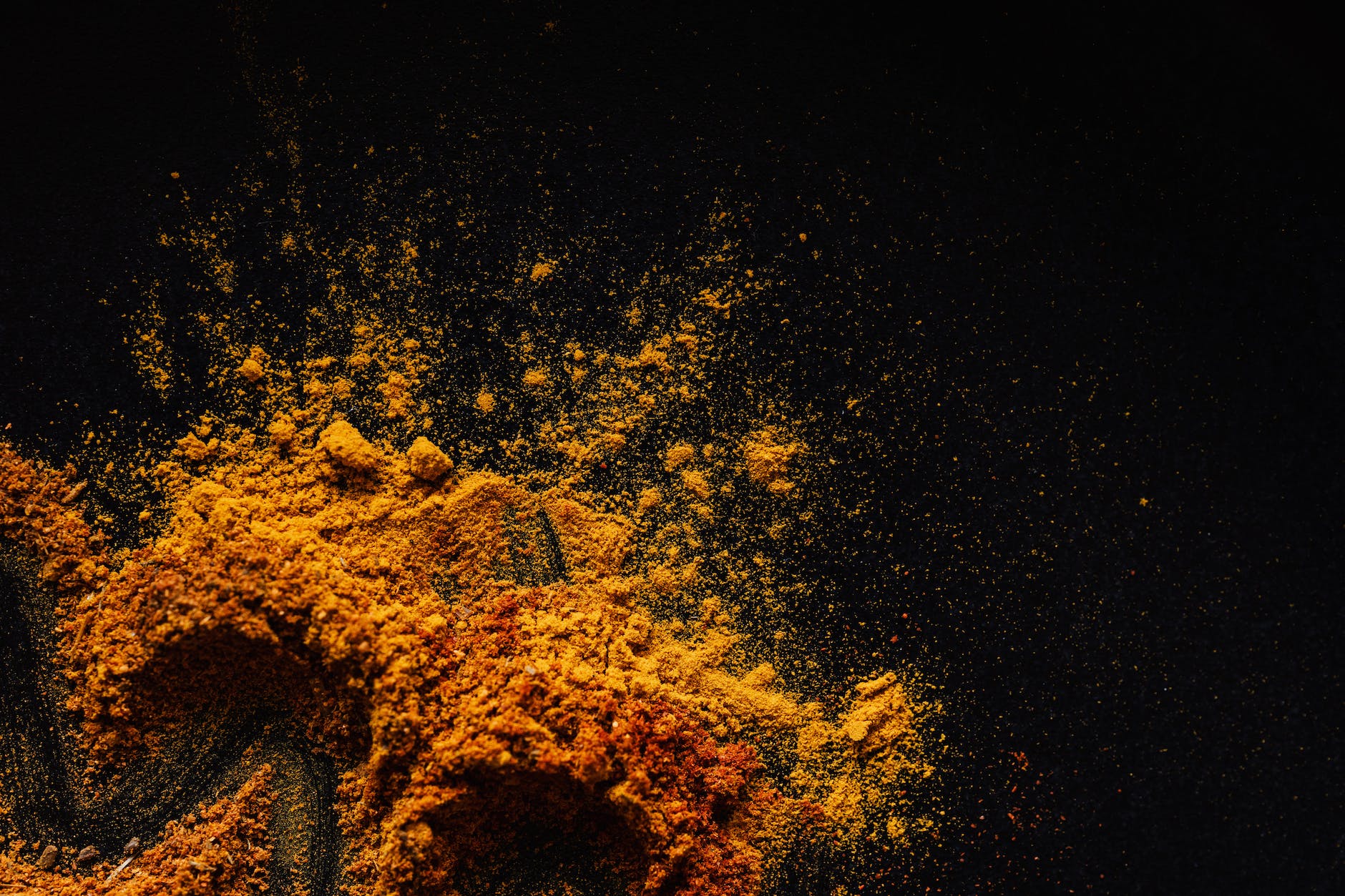 composition of multicolored ground spices spilled on black background
